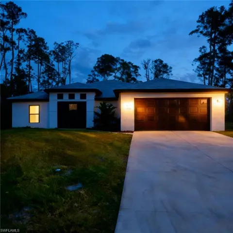 View of front of property with driveway, stucco siding, and a front yard