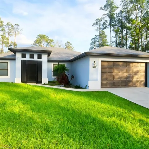 View of front facade with a front yard, stucco siding, concrete driveway, and an attached garage