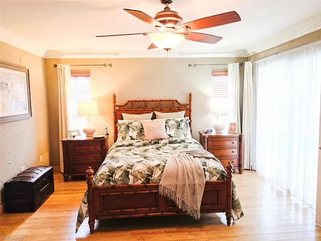 Wood-finish flooring, crown molding, ceiling fan with integrated lighting, and a window with blinds and drapes