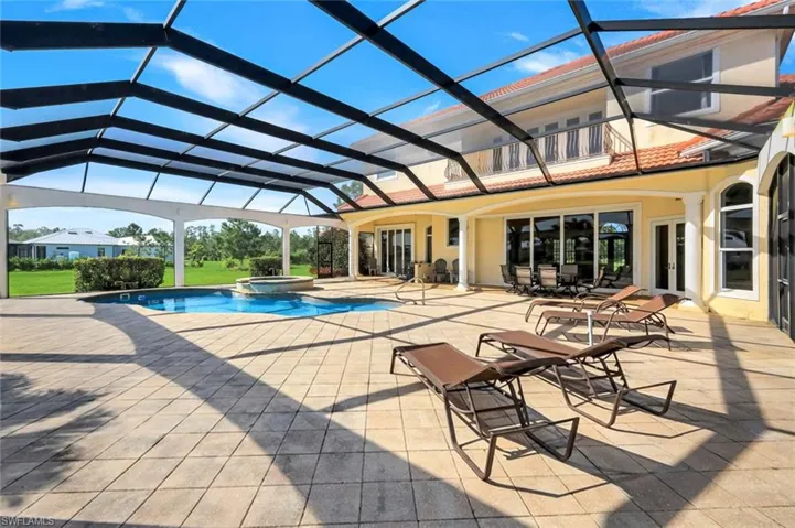 Screened outdoor living area with a built-in pool and spa, expansive paver patio, and covered terrace