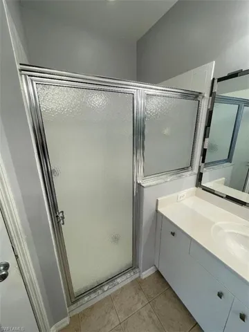 Bathroom with tile patterned floors, a shower with door, and vanity