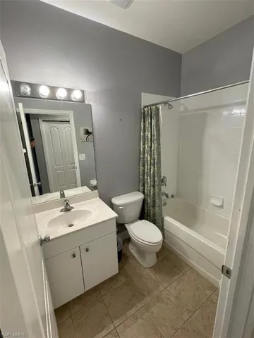 Full bathroom with toilet, shower / bath combo, vanity, and tile patterned floors