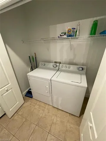 Laundry area with washer and clothes dryer and light tile patterned flooring