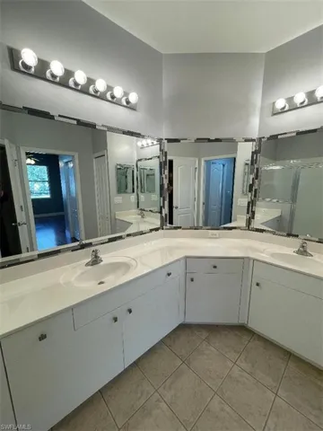 Master Bathroom featuring tile patterned floors, vanity, ceiling fan, and an enclosed shower and dual sinks