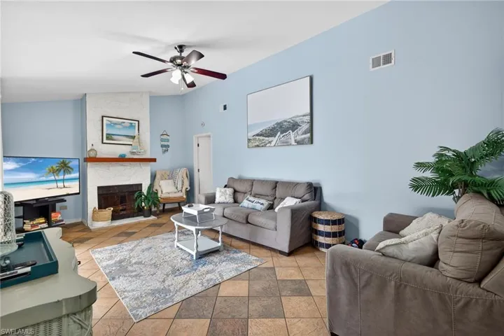 Living area with a large fireplace, ceiling fan, and lofted ceiling