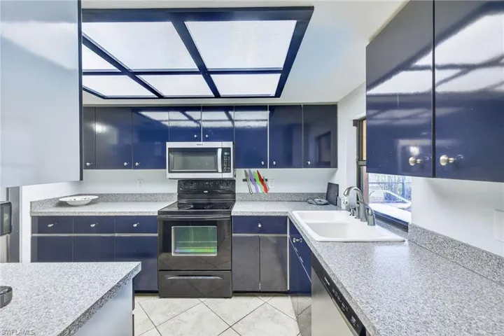Kitchen featuring stainless steel appliances, light tile patterned flooring, light countertops, and blue cabinetry
