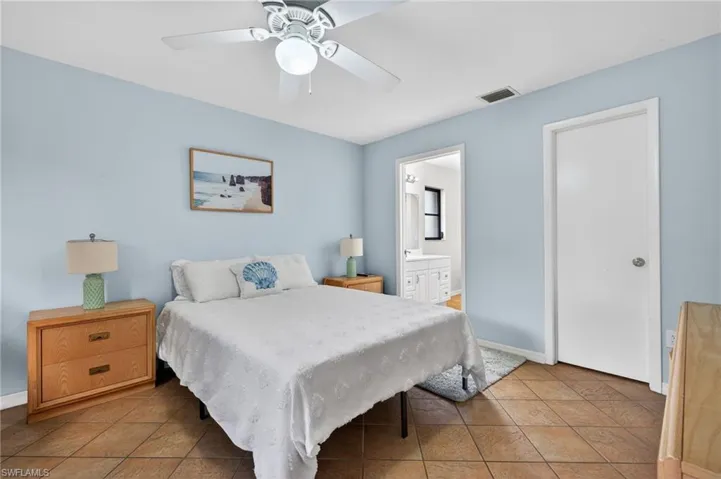 Bedroom with ceiling fan, ensuite bathroom, and light tile patterned floors