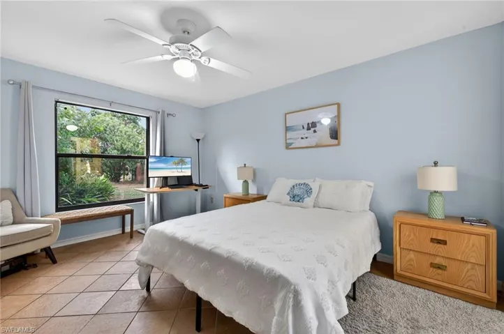 Tiled bedroom with a ceiling fan and baseboards