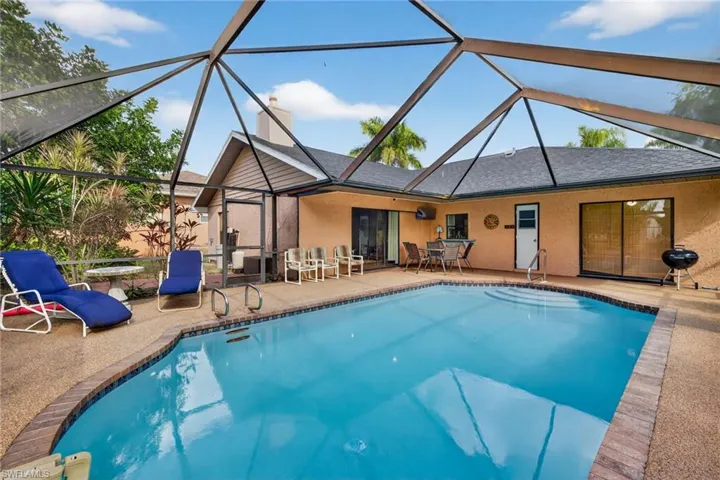 Swimming pool featuring a screencage, a patio area, glass enclosure, grilling area, and outdoor dining area