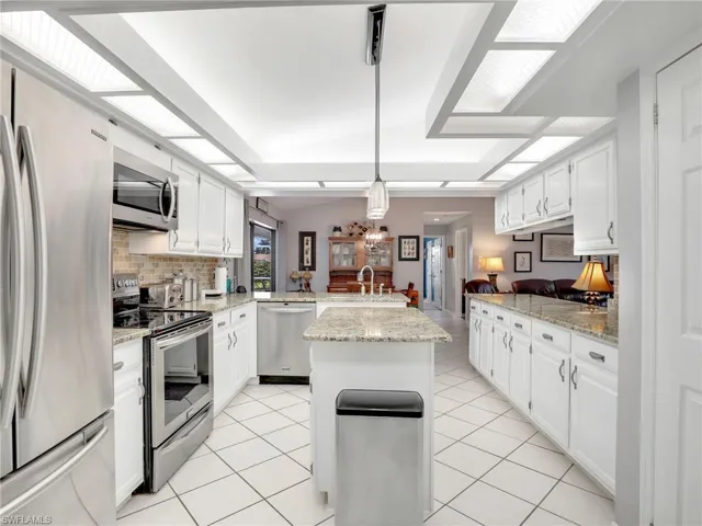 Kitchen featuring a center island, light tile flooring, white cabinetry, and appliances with stainless steel finishes