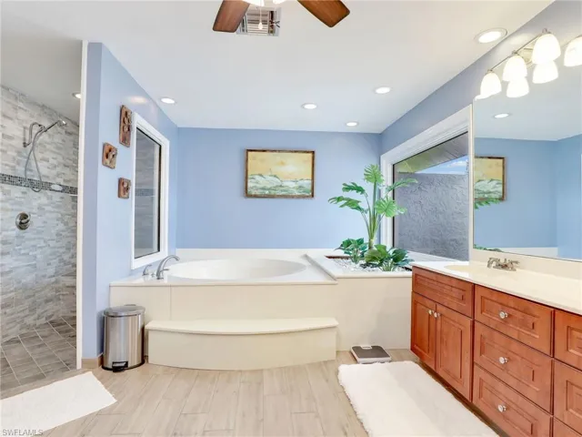 Bathroom with large walk-in tiled shower, Soaker tub shower, dual sinks, water closet, and ceiling fan