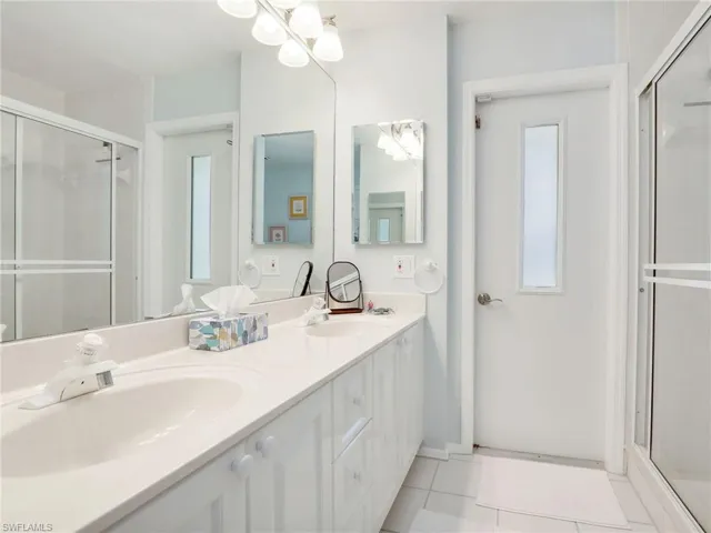 Guest bathroom with access to pool area, shower/tub combo, and dual sinks