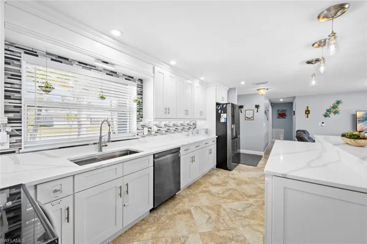 Kitchen featuring white cabinets, appliances with stainless steel finishes, a sink, beverage cooler, and backsplash