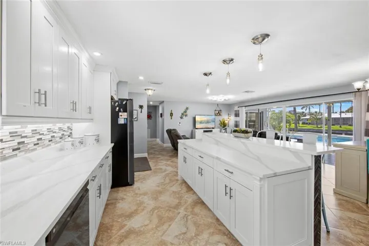 Kitchen featuring tasteful backsplash, open floor plan, a center island, and freestanding refrigerator