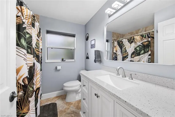 Guess Bathroom with a shower with curtain, baseboards, toilet, and vanity