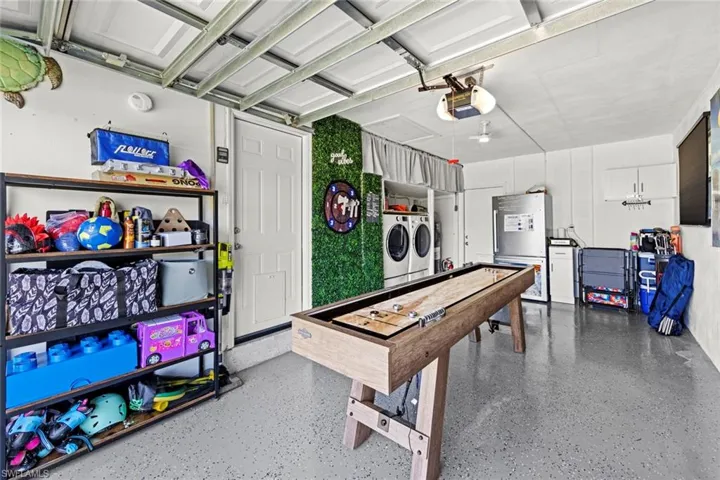 Game room featuring washing machine and clothes dryer, a garage, and speckled floor
