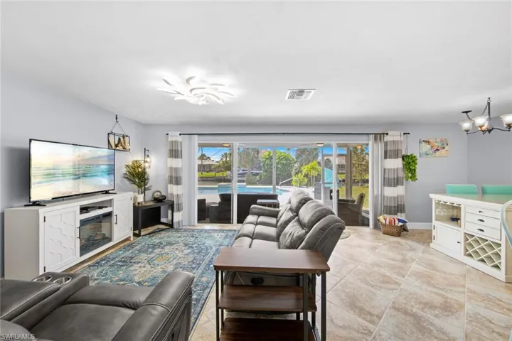 Living area with baseboards and an inviting chandelier that is also a fan