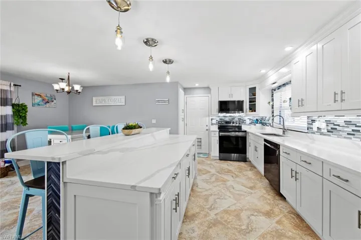 Kitchen with a center island, a breakfast bar, a sink, stainless steel range with electric cooktop, and dishwasher