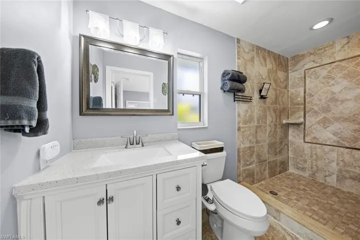 Primary Bathroom featuring a tile shower, toilet, and vanity