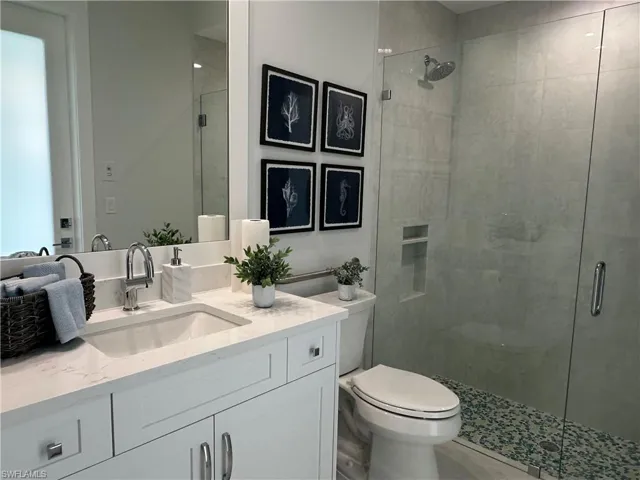 Bathroom with toilet, a shower with door, and vanity