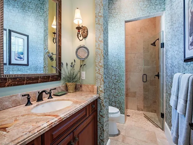 Bathroom featuring vanity, a shower stall, and wallpapered walls