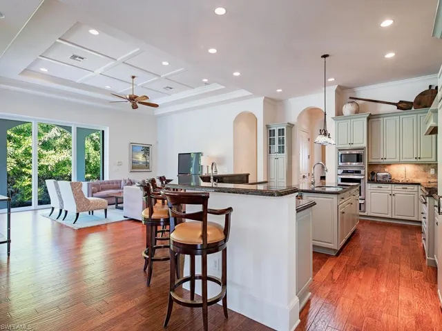 Kitchen with arched walkways, recessed lighting, open floor plan, decorative backsplash, and dark stone countertops