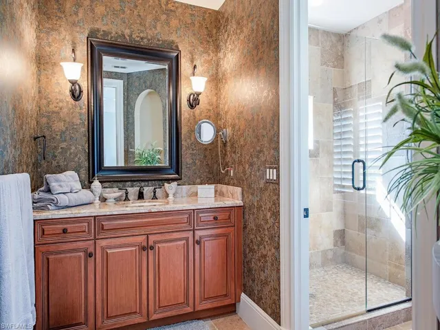 Full bath featuring a stall shower, vanity, light tile patterned flooring, and wallpapered walls