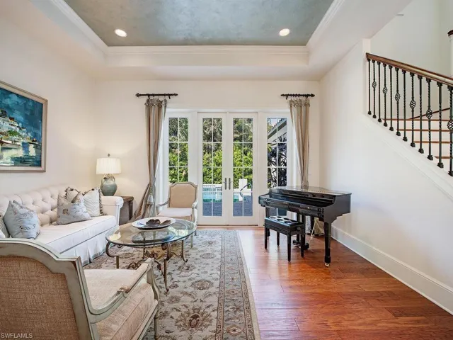 Living room with hardwood / wood-style floors, stairs, french doors, a raised ceiling, and ornamental molding