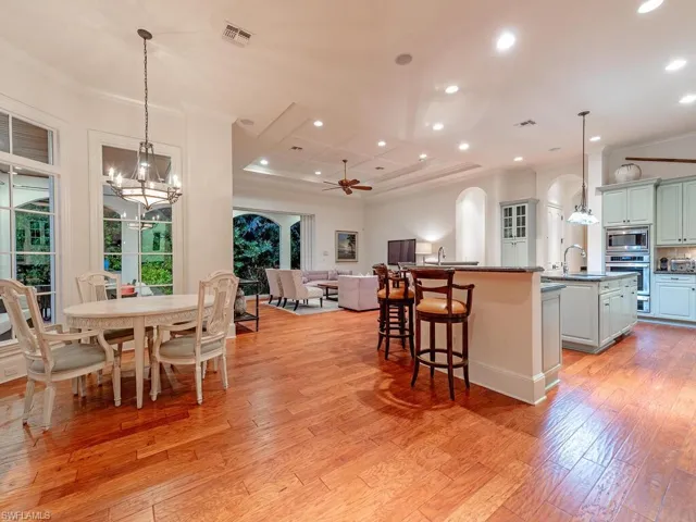 Kitchen featuring pendant lighting, a ceiling fan, crown molding, a breakfast bar, and light wood-type flooring