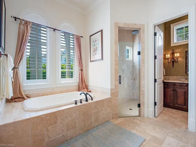 Full bath with a stall shower, healthy amount of natural light, vanity, a garden tub, and ornamental molding