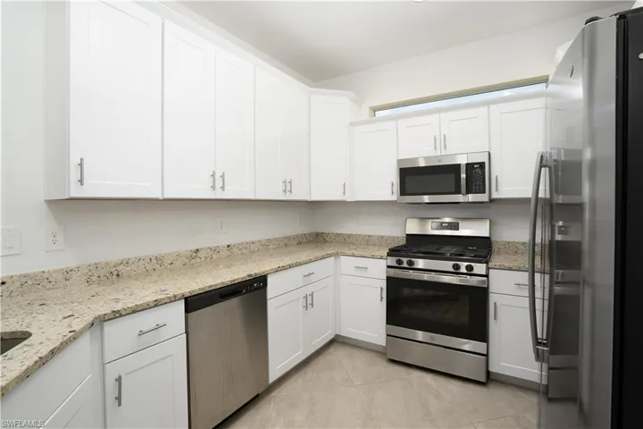 Crisp white shaker style cabinetry in the kitchen, with stainless steel appliance package including a natural gas stove and granite counter tops.