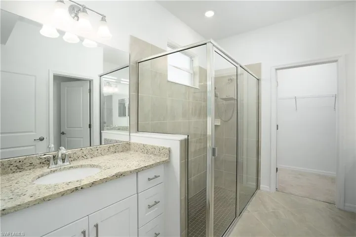 Primary bath with separate vanities, glass shower enclosure and water closet.