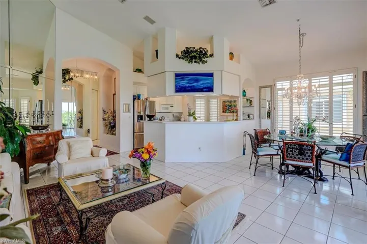 Living room with arched walkways, a notable chandelier, and light tile patterned floors