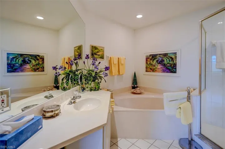 Bathroom featuring recessed lighting, a bath, vanity, and a stall shower