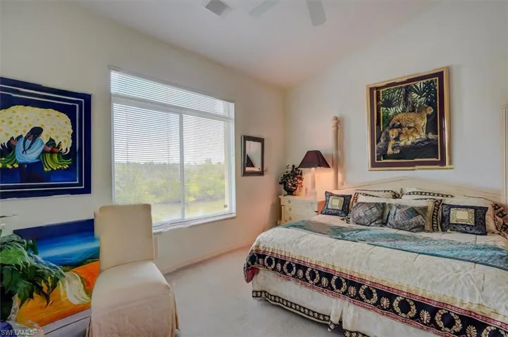 Carpeted bedroom featuring lofted ceiling, a ceiling fan and multiple windows