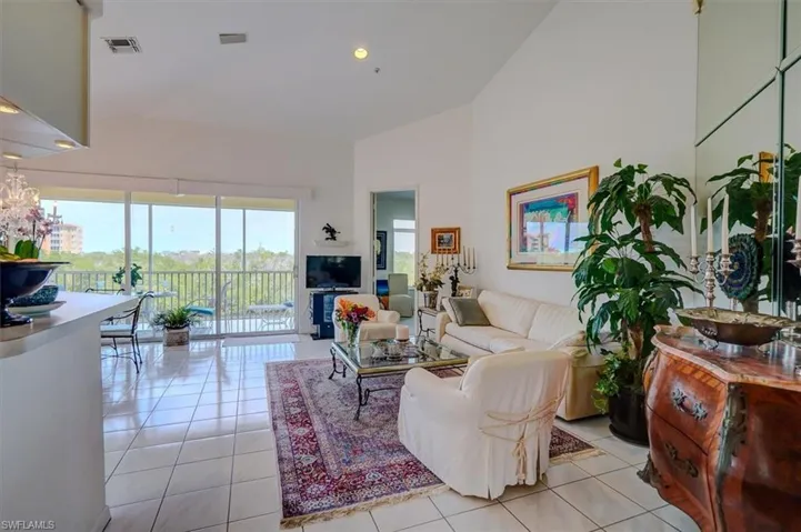 Living area with light tile patterned flooring, visible vents, a wealth of natural light, and high vaulted ceiling