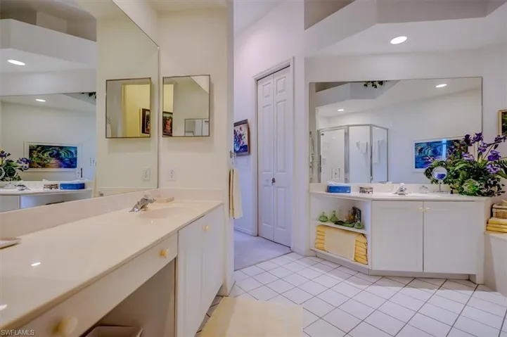 Primary Bathroom with two sinks & vanities, a shower stall, tile patterned flooring