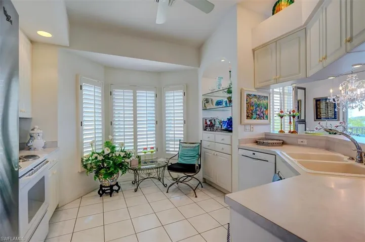 Kitchen featuring a sink, ceiling fan with notable chandelier, white appliances, light tile patterned floors, and light countertops