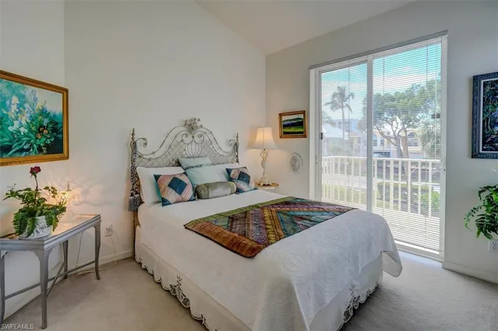 Bedroom with vaulted ceiling, light carpet, access to exterior, and baseboards