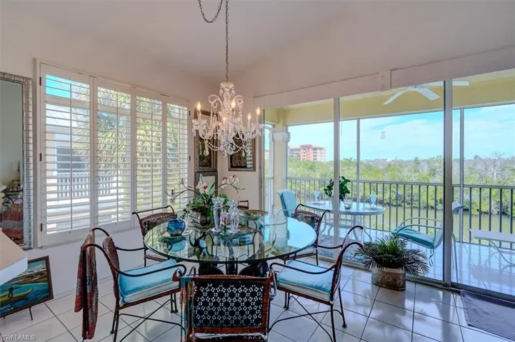 Dining space with vaulted ceiling, tile patterned flooring, and a chandelier