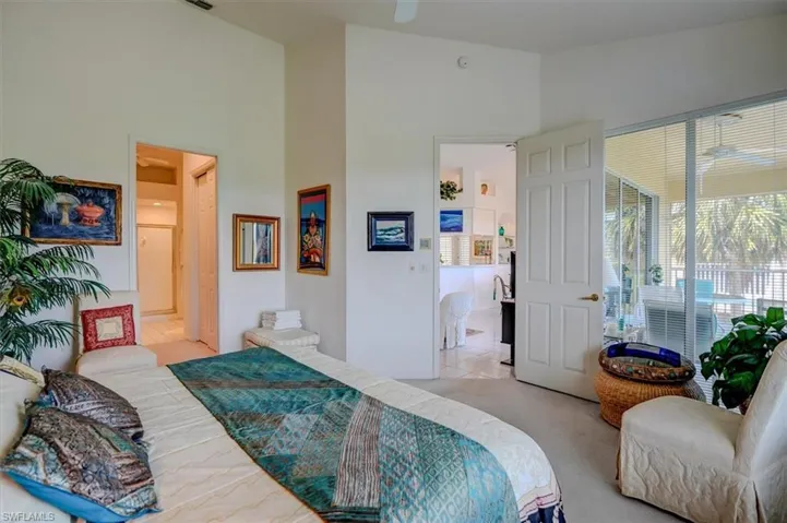 Primary Bedroom featuring high vaulted ceiling, light colored carpet, multiple windows, and connected bathroom