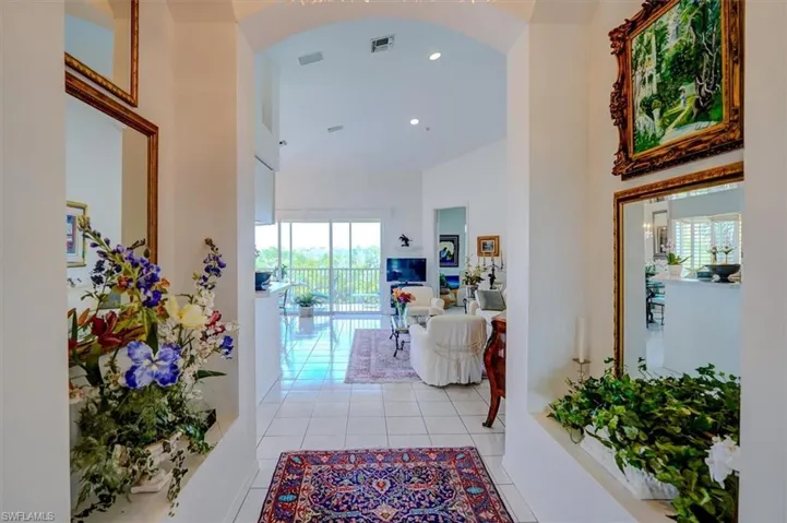 Foyer with light tile patterned floors, arched walkways, high ceiling and recessed lighting