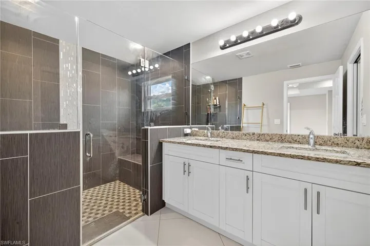 Bathroom featuring double vanity, light tile patterned floors, and a stall shower