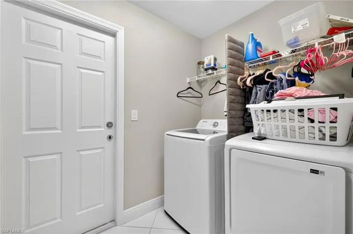 Laundry area featuring light tile patterned floors and washing machine and clothes dryer