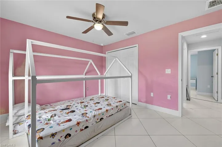 Bedroom with light tile patterned floors, ceiling fan, and a closet
