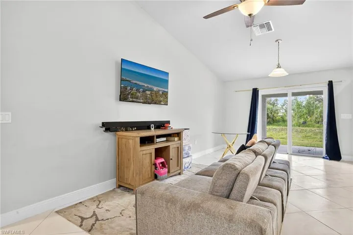 Living area featuring light tile patterned flooring, lofted ceiling, and a ceiling fan