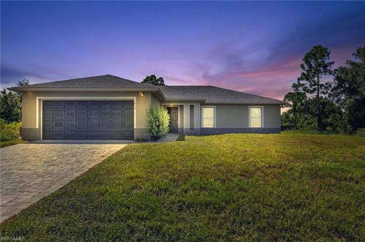 View of front of property with stucco siding, a lawn, decorative driveway, an attached garage, and a shingled roof