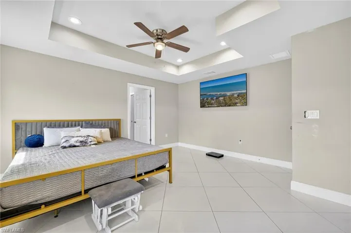 Bedroom featuring a raised ceiling, light tile patterned flooring, ceiling fan, and recessed lighting