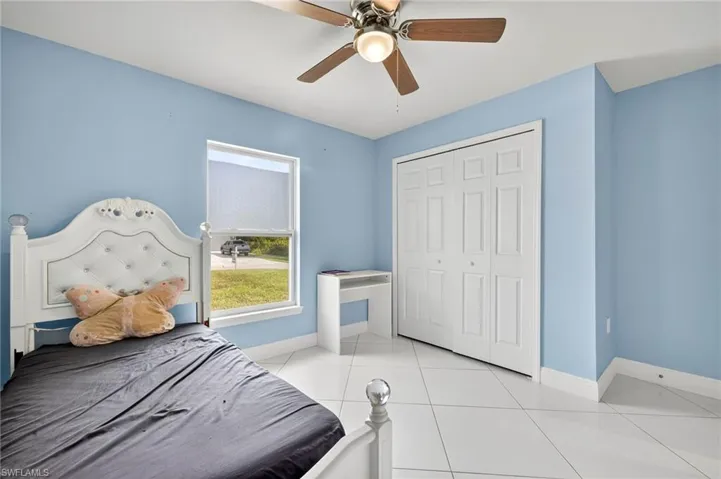 Bedroom featuring light tile patterned floors, a closet, and a ceiling fan