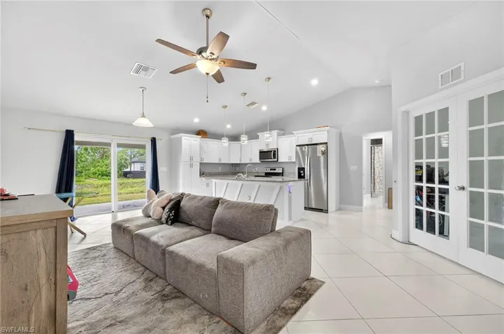 Living area with ceiling fan, light tile patterned floors, high vaulted ceiling, and recessed lighting